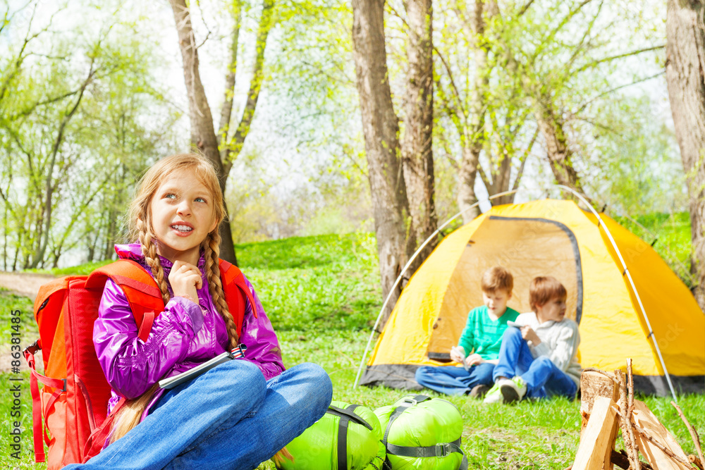 Looking girl with red backpack rests in camp