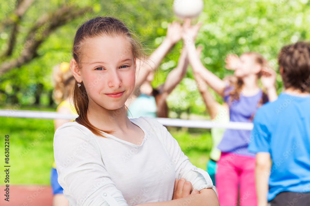 Portrait of teen girl with team playing volleyball