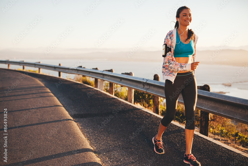 快乐的年轻女子在乡村公路上奔跑