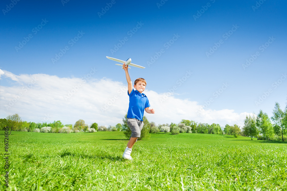 Happy boy holding airplane toy during running