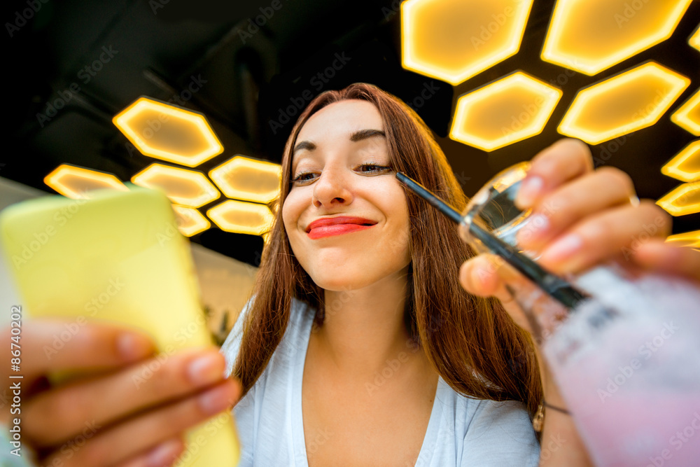 Woman with phone and drink in modern interior