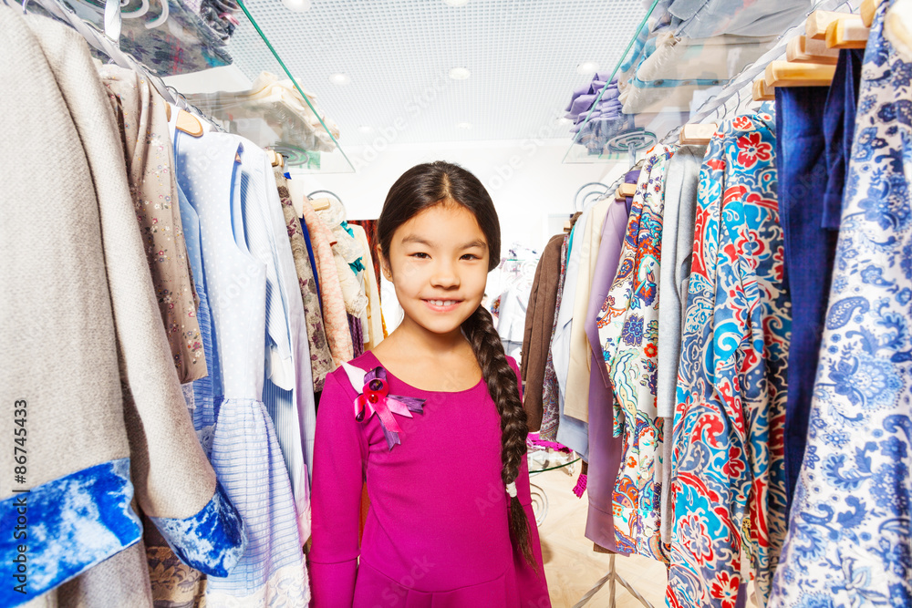 Small girl with braid between clothes hangers