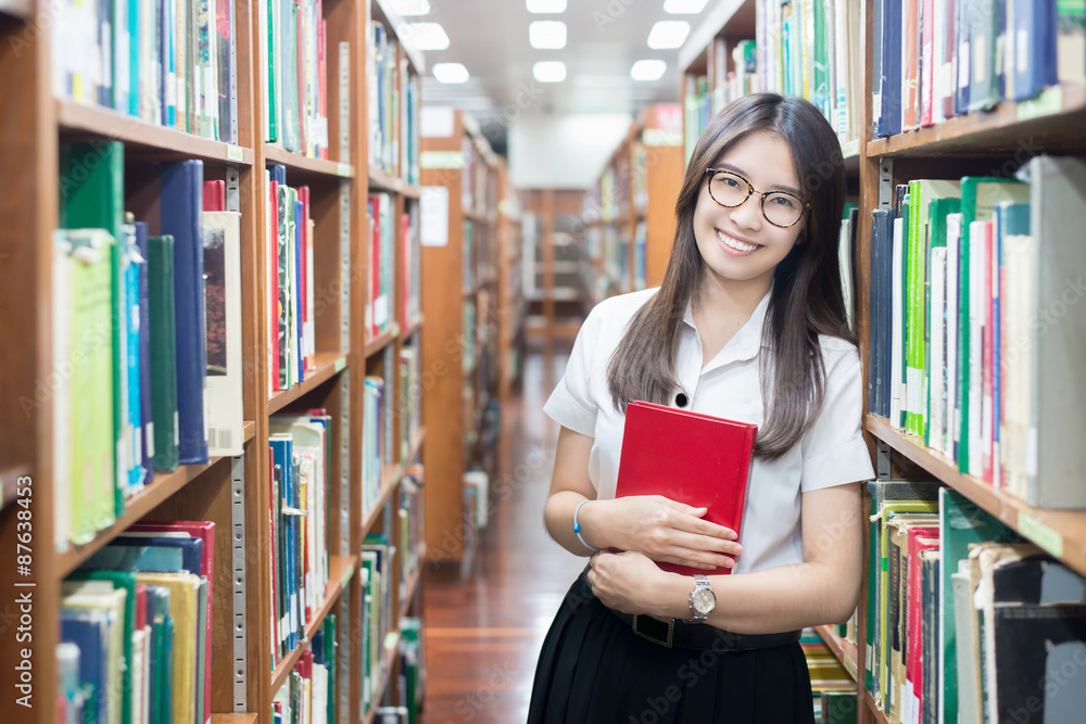 穿着制服的亚洲学生在大学图书馆阅读