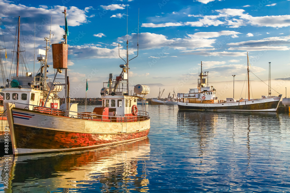 Traditional old fisherman boats lying in harbor in beautiful golden evening light at sunset, Iceland