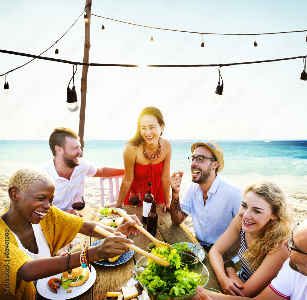 朋友们在夏季海滩聚会上用餐愉快的概念