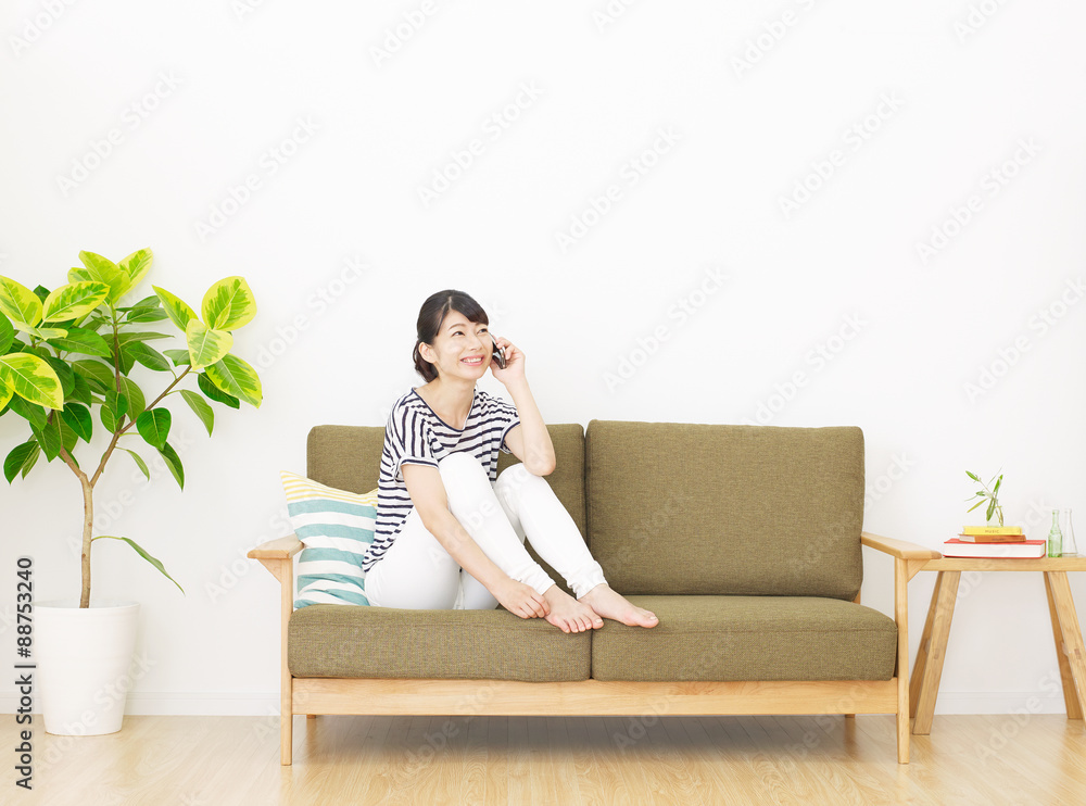 部屋でスマホで話す女性