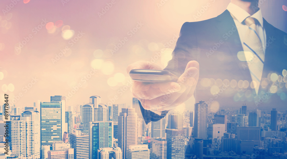 Double exposure of young businessman holding a smartphone