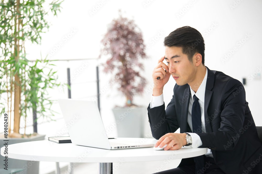 Young asian businessman using tablet, mobile phone in the office