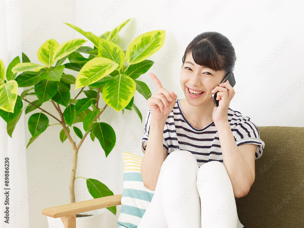 部屋でスマートフォンで話す女性　指差し