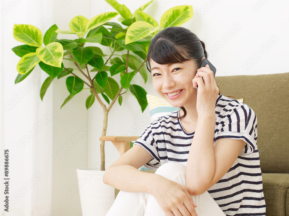 部屋でスマートフォンで話す女性