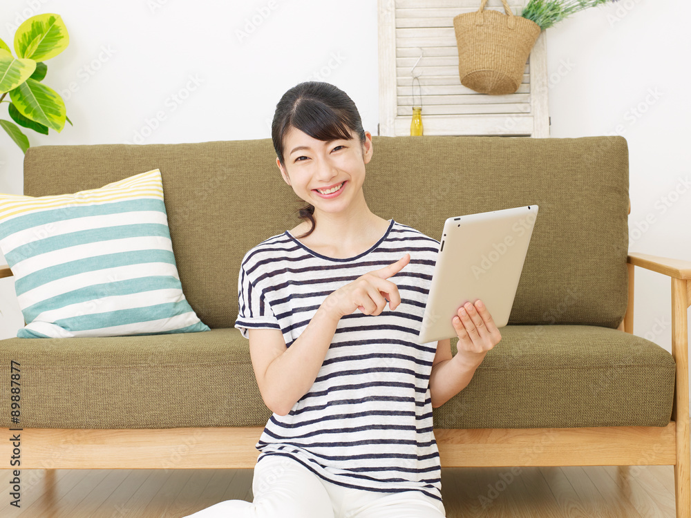 部屋でタブレットを使う女性