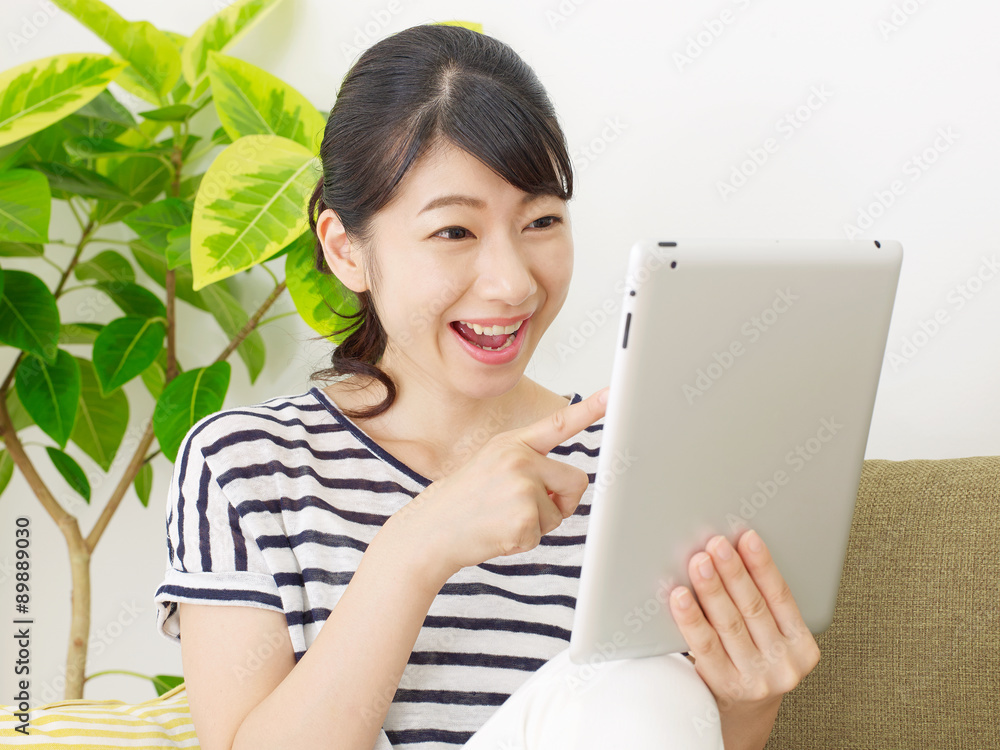 部屋でタブレットを使う女性