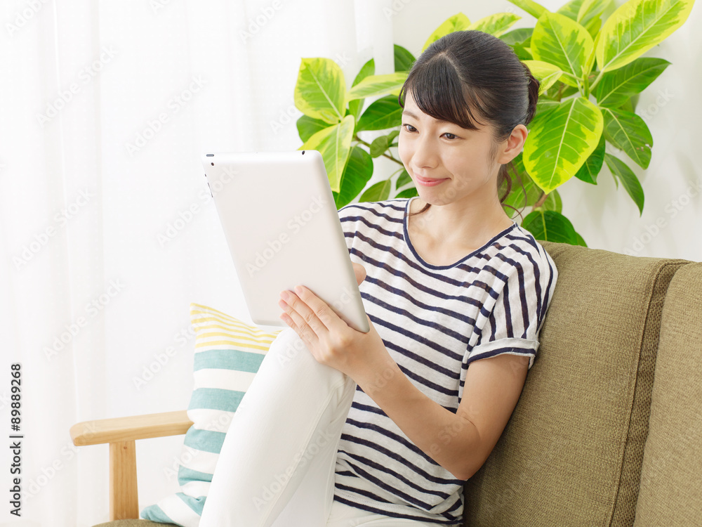 部屋でタブレットを使う女性