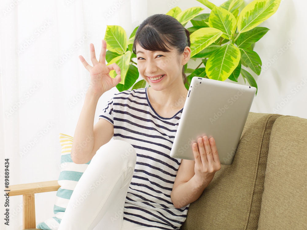 部屋でタブレットを使う女性　OKサイン