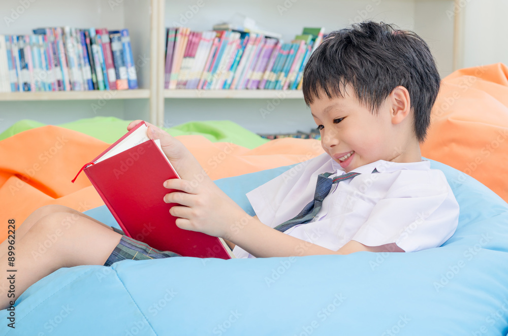 穿着制服的亚洲男生在学校图书馆看书