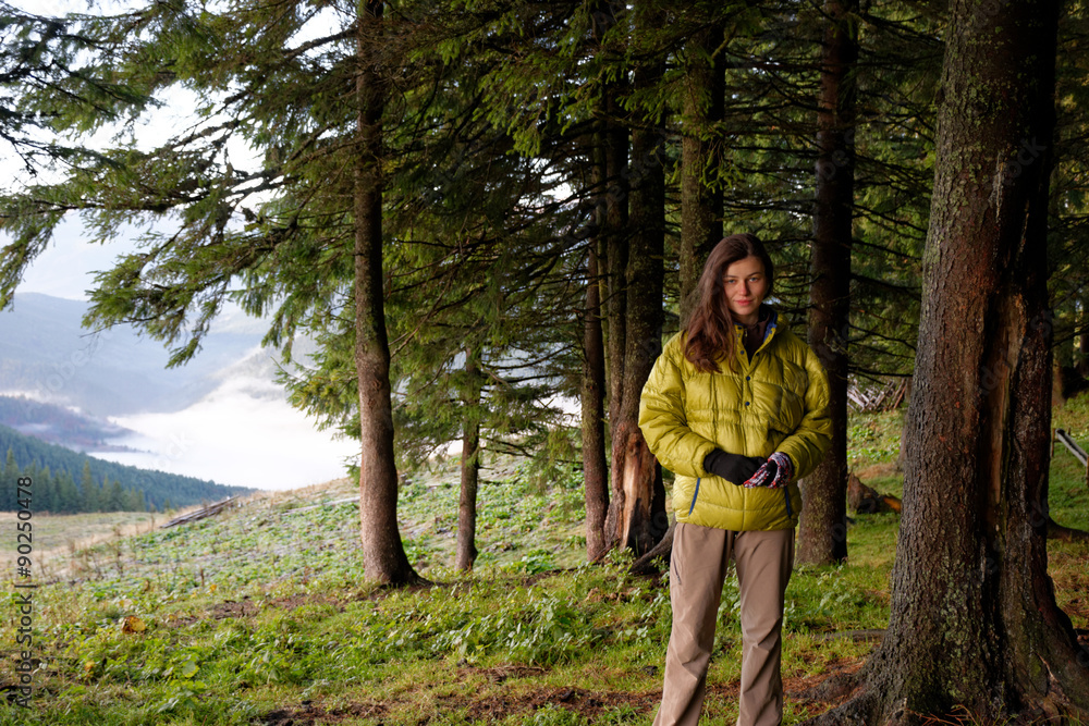 Portrait of girl in yellow down jacket in the autumn mountains with mist in the valleys