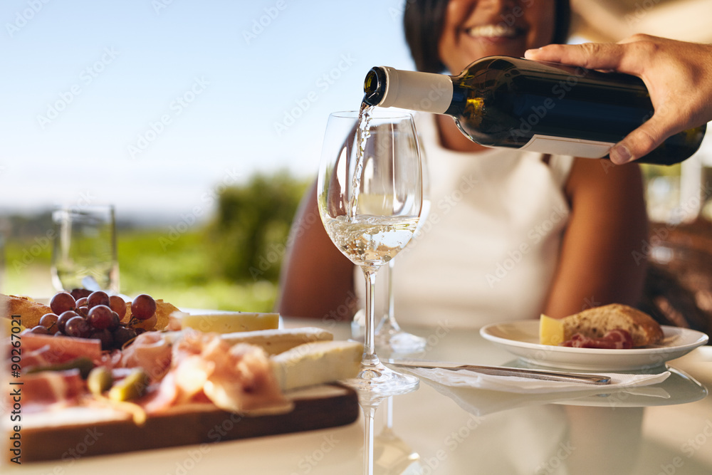 Human hand pouring white wine from a bottle