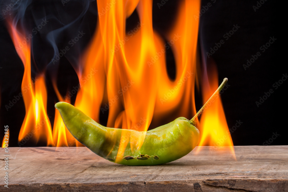 green pepper with flame on black background