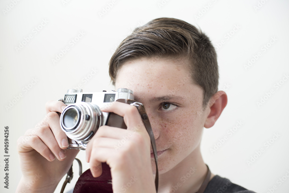 Boy holds retro style 35mm camera ready to take a picture