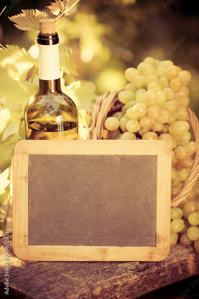 Wooden blackboard blank, wine bottle and grapes of vine