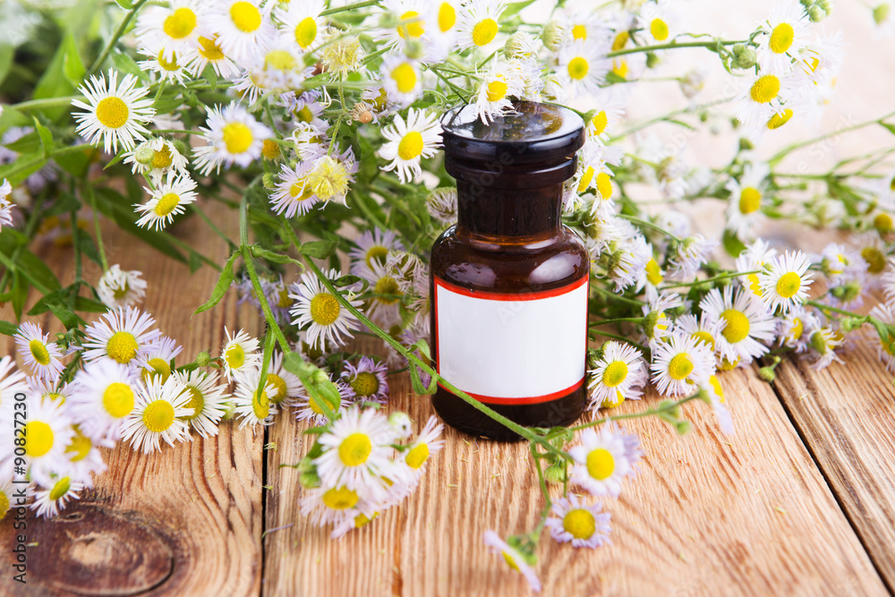 Herbal medicine concept - bottle with camomile on wooden table