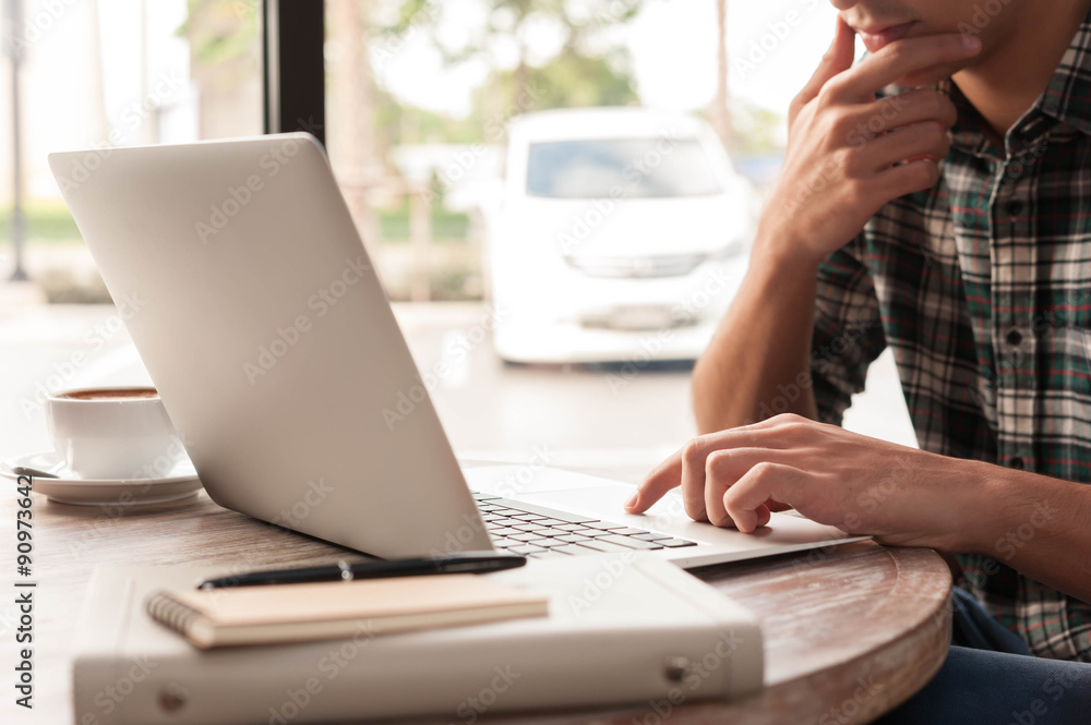 Businessman using laptop with tablet and pen on wooden table in