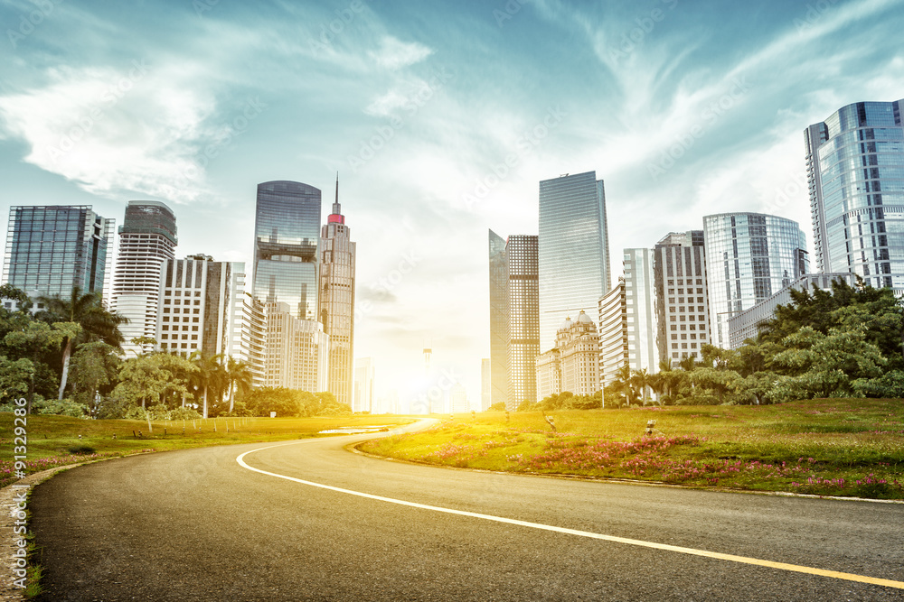 asphalt road and skyscrapers under sunbeam