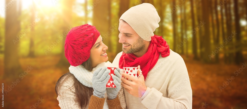 Composite image of winter couple holding mugs