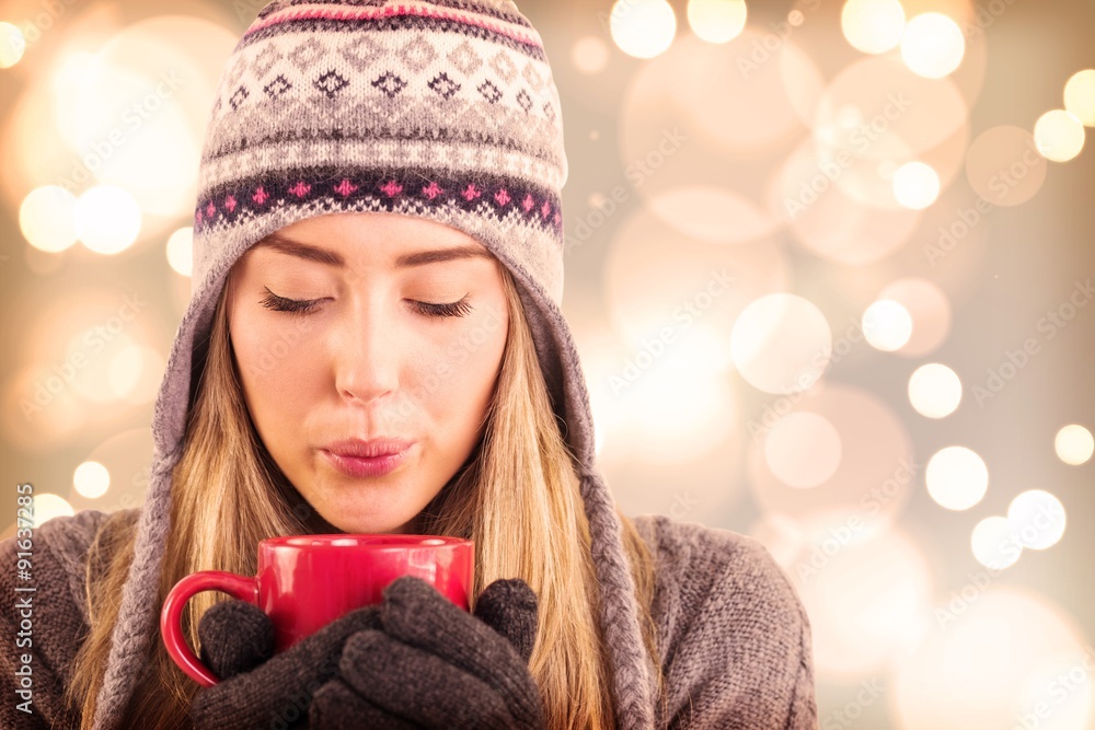 Composite image of happy blonde in winter clothes holding mug