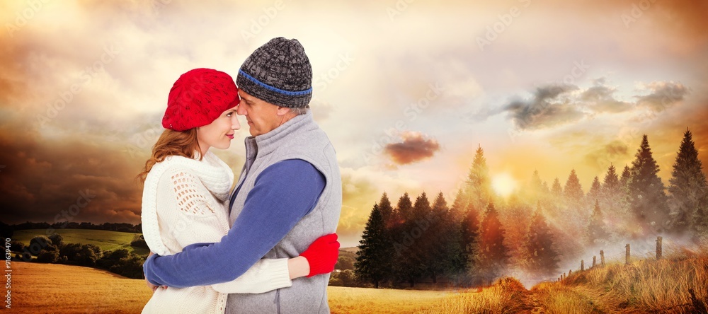 Composite image of happy couple in warm clothing hugging