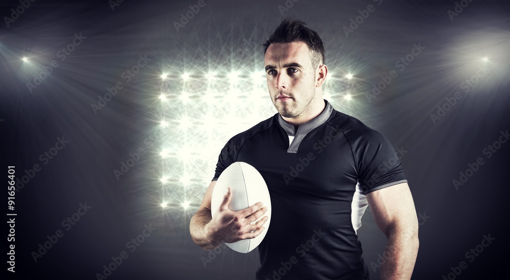 Composite image of tough rugby player holding ball