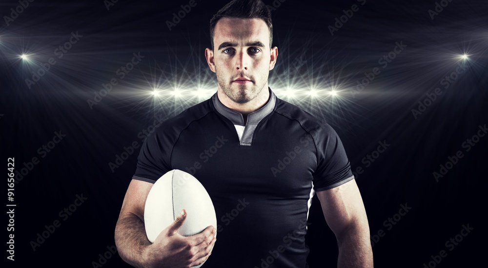 Composite image of tough rugby player holding ball