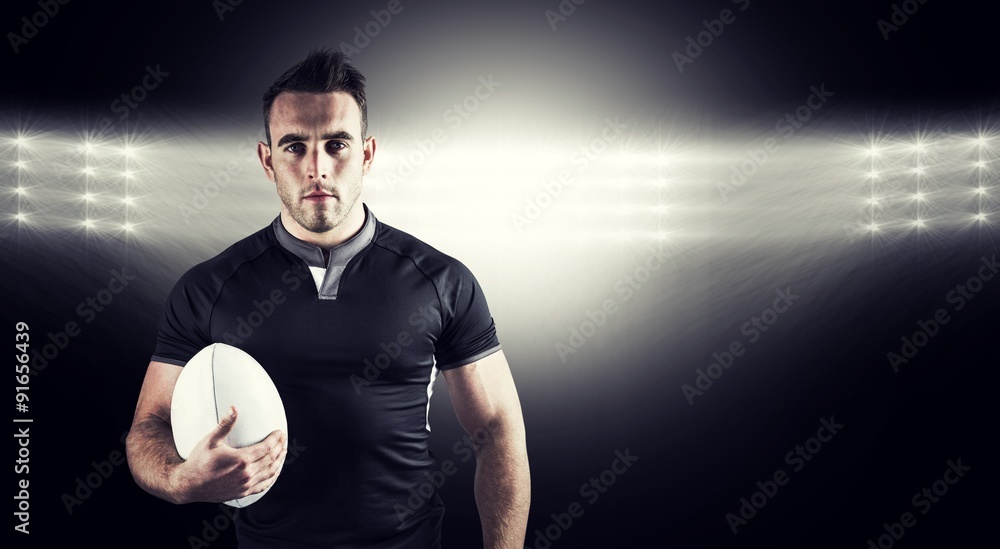 Composite image of tough rugby player holding ball