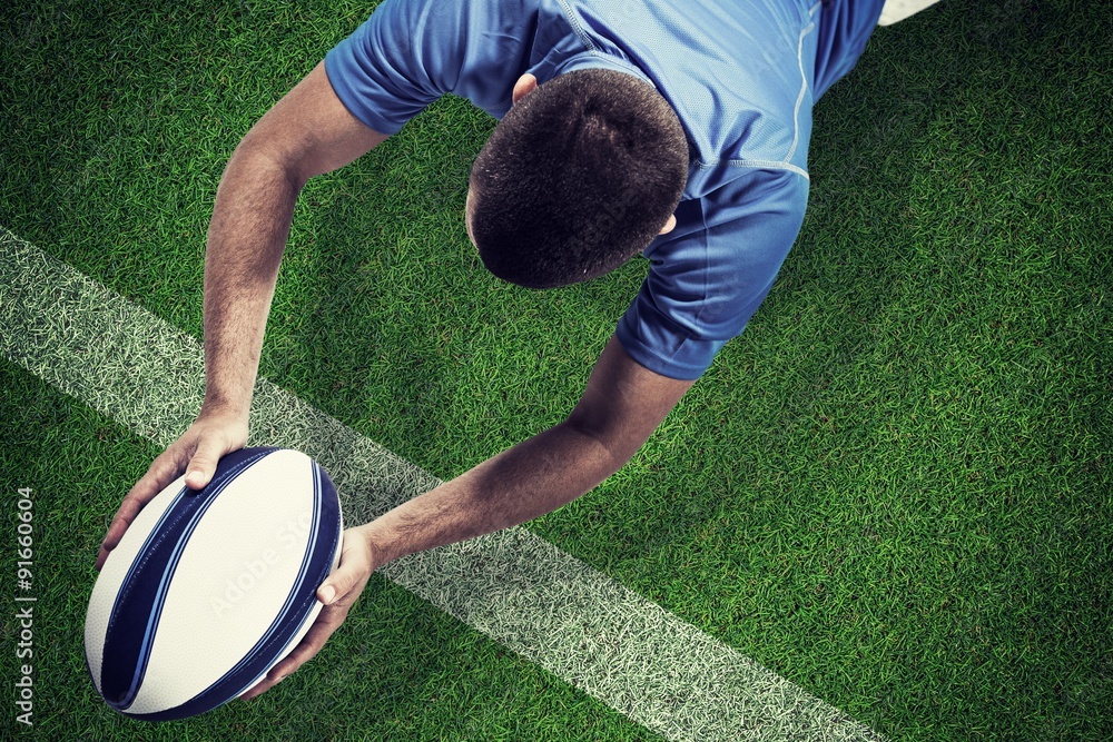 Composite image of rugby player lying in front with ball