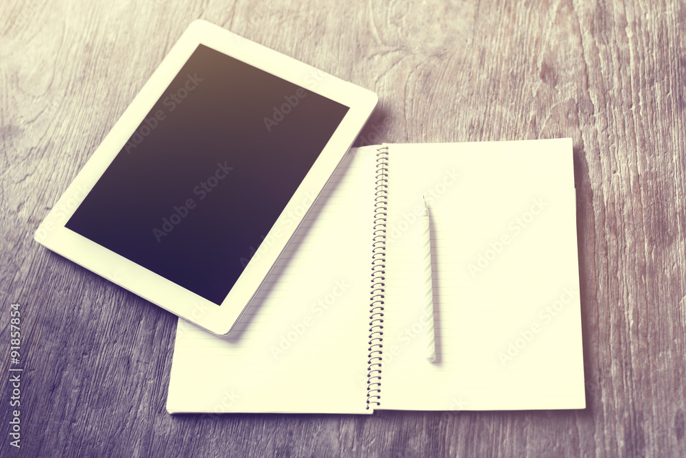 Blank digital tablet, diary and pen on a wooden table, vintage p