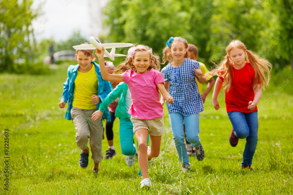 View of girl holding airplane toy and kids behind