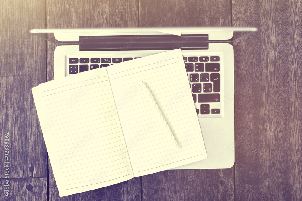 Blank diary with pencil with laptop on a wooden table