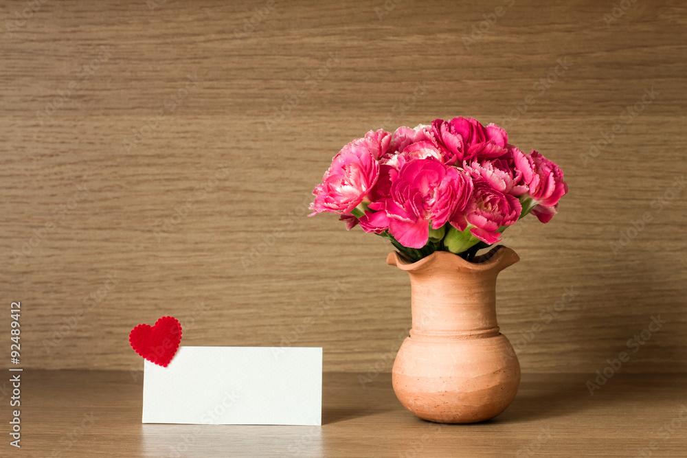 Fresh pink carnation flower and blank card for copy space over w