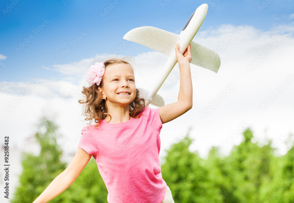 Happy girl holds white airplane toy with arm