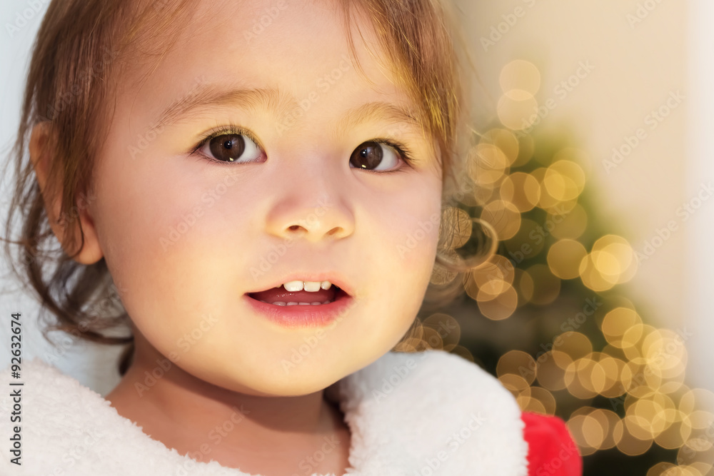 Little girl smiling in front of her Christmas tree