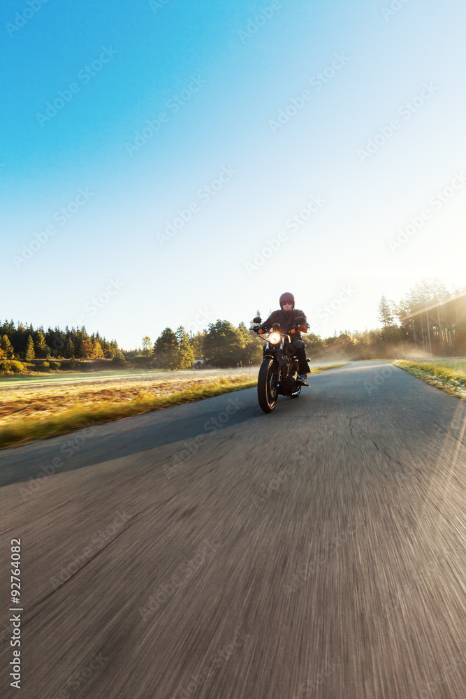 A young man riding a chopper on a road