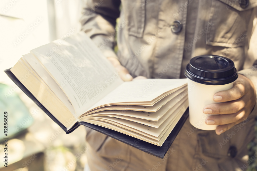 Hipster girl is reading a book and drinking a coffee