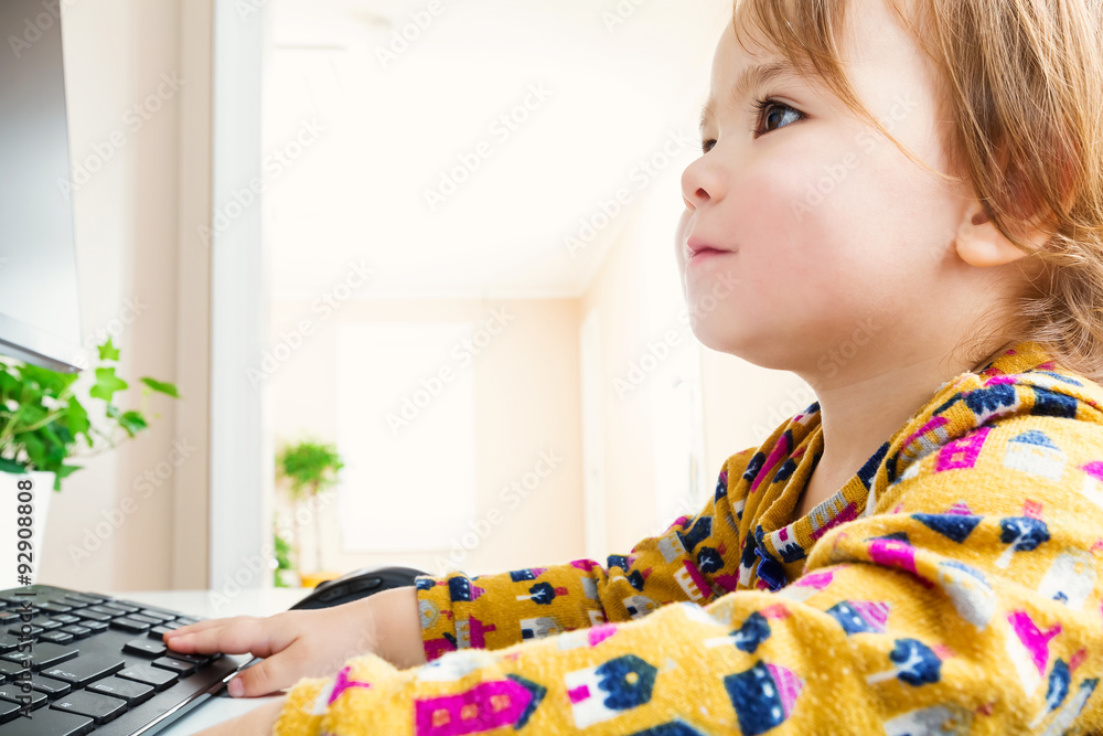 Happy toddler girl enjoying her computer