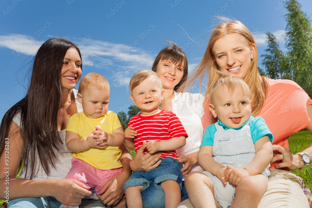 Mothers holding cute babies sitting together