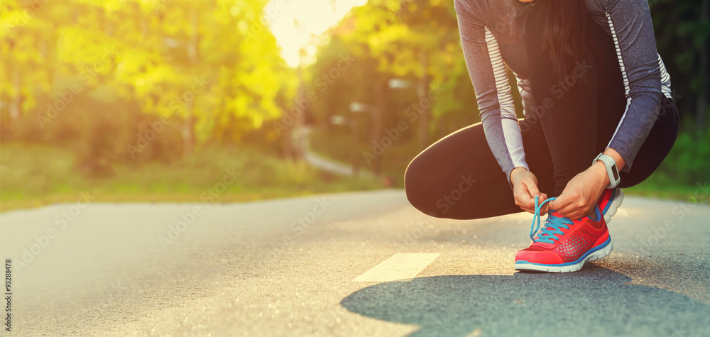 Female runner tying her shoes preparing for a jog