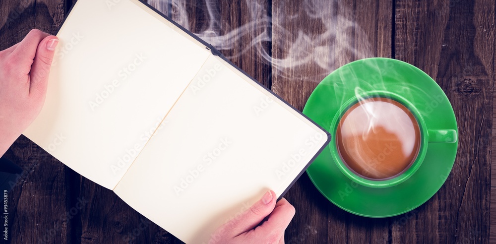 Overhead view of hot tea by hand holding book