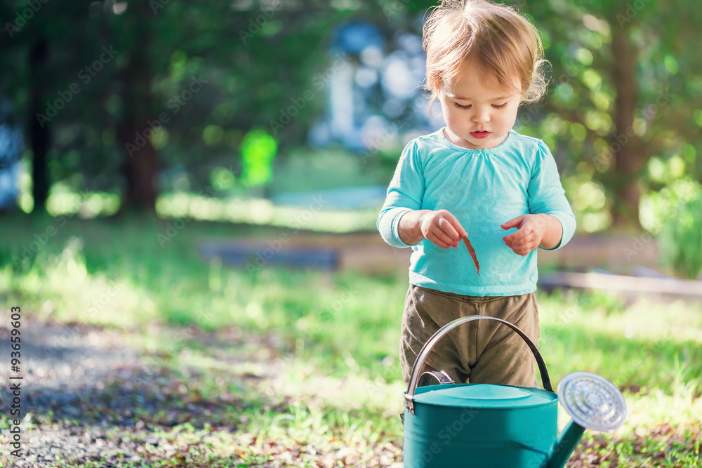 Happy toddler girl playing with a watering can