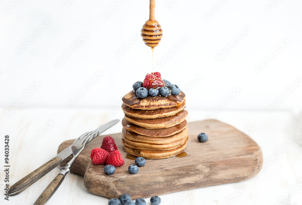 Buckwheat pancakes with fresh berries and honey on rustic wooden