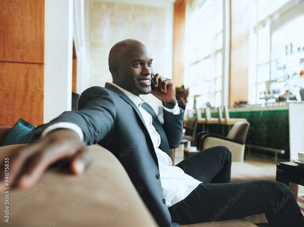 Happy young businessman waiting at hotel lobby making a phone ca