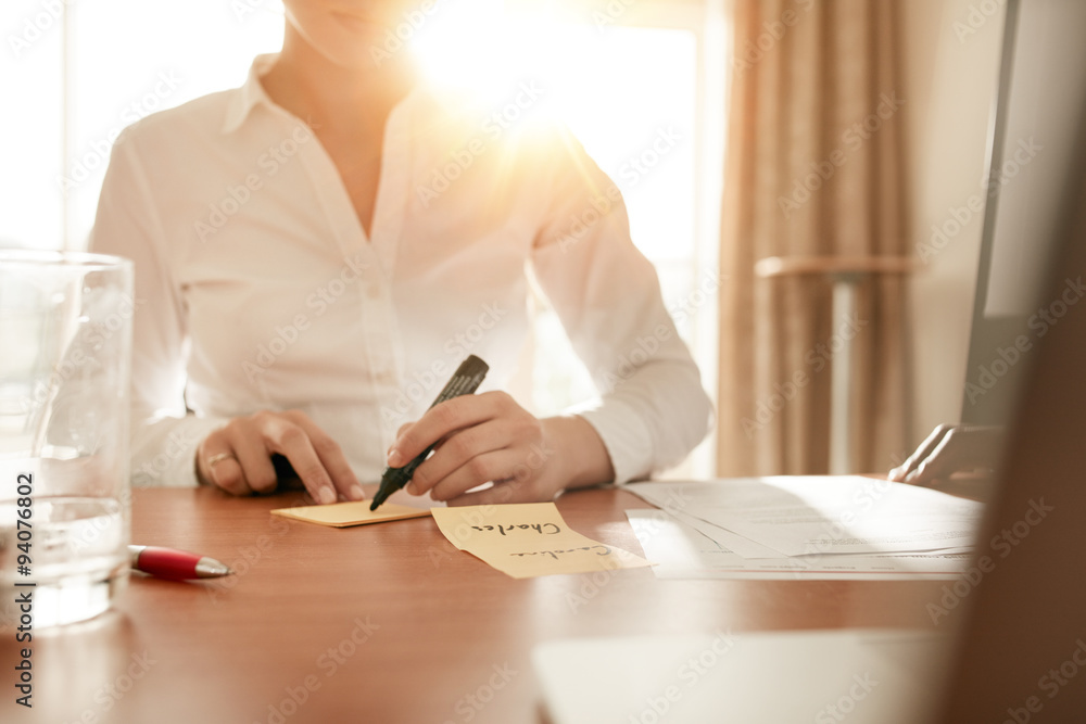 Woman writing on sticky notes at conference room